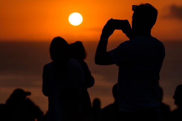 People gather to watch the sunset at "El Rayo Verde" viewpoint, in San Vicente de la Barquera in the province of Cantabria, northern Spain, on August 9, 2026. Spain, one of the few places in the world where the solar eclipse of August 12 will be seen in totality, is beginning preparations for a phenomenon expected to shift traditional summer tourism from beaches to the countryside. (Photo by CESAR MANSO / AFP)