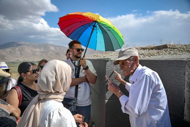 Mehmet Kusman, aged 86, who speaks Urartian language, reads a tablet engraved with Urartu language at the fortress of Cavustepe near Van, in eastern Turkey, on July 22, 2026. Mehmet Kusman, 86, has dedicated his life to the Cavustepe Fortress in eastern Turkey and to studying the Urartian language, which borrows its cuneiform alphabet from Assyrian to honor the gods and rulers of the lost kingdom. (Photo by Ozan KOSE / AFP)
