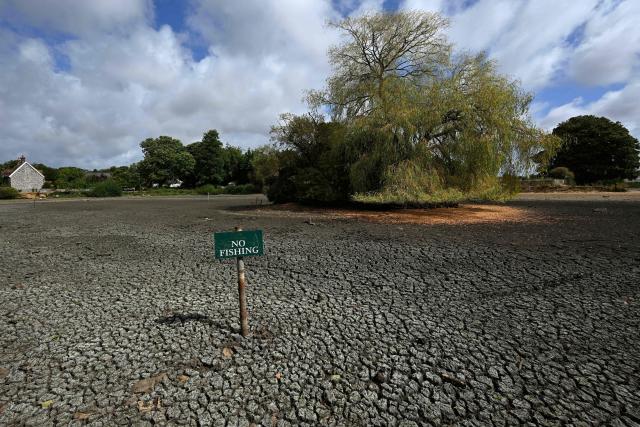 (FILES) A ’No Fishing’ sign is pictured in the dried up Falmer Pond in Falmer, East Sussex, south of London on August 5, 2026. Climate change has intensified a drought across Europe this summer, with extreme heat driving the exceptionally dry conditions, according to experts. (Photo by GLYN KIRK / AFP)