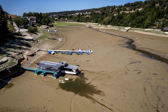 (FILES) This aerial view shows the parched bed of Brenets Lake (Lac des Brenets), part of the Doubs River, a natural border between eastern France and western Switzerland, as central Europe is in a third heatwave since June, in Les Brenets on July 28, 2026. Climate change has intensified a drought across Europe this summer, with extreme heat driving the exceptionally dry conditions, according to experts. (Photo by Fabrice COFFRINI / AFP)