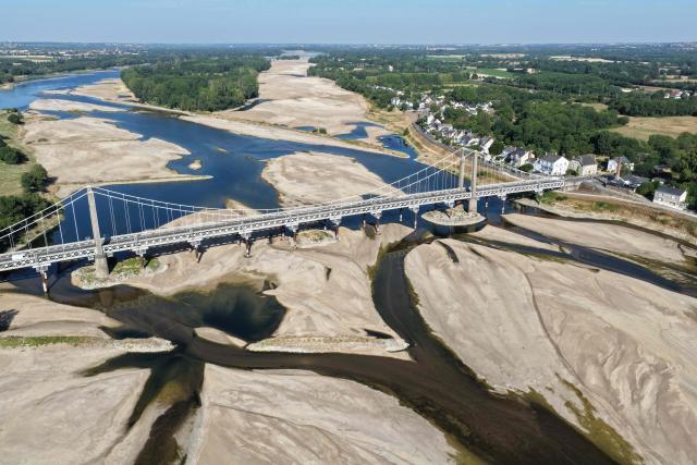 (FILES) This aerial photograph shows a bridge over the dried out Loire River bed in Loireauxence (Varades), western France, on July 10, 2026. Climate change has intensified a drought across Europe this summer, with extreme heat driving the exceptionally dry conditions, according to experts. (Photo by Damien MEYER / AFP)