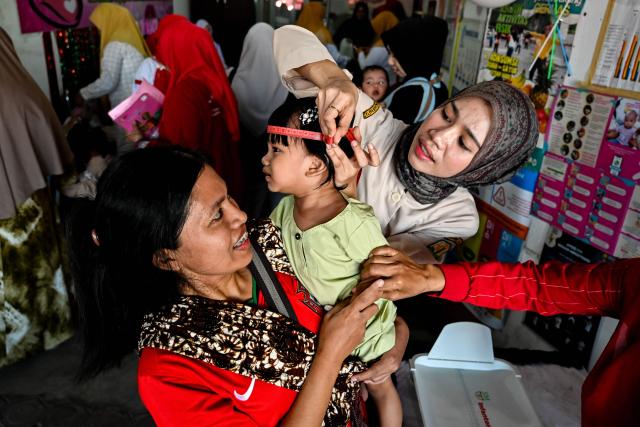 A health worker measures the growth of a child during a monthly medical check-up program for children at an integrated services centre in Banda Aceh on August 10, 2026. (Photo by CHAIDEER MAHYUDDIN / AFP)