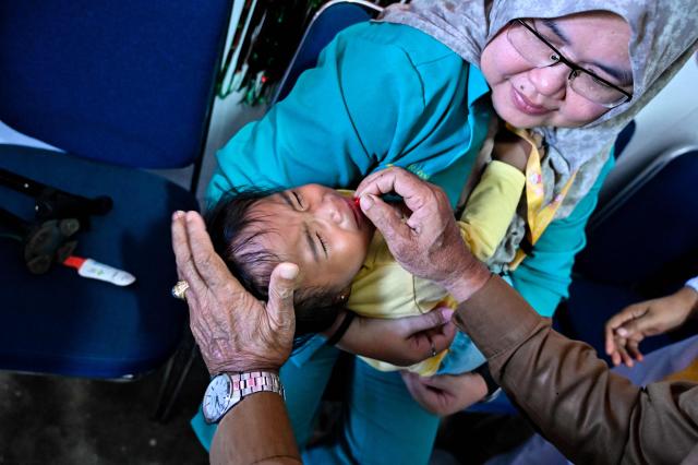 A toddler receives a vitamin A supplement during a monthly medical check-up program for children at an integrated services centre in Banda Aceh on August 10, 2026. (Photo by CHAIDEER MAHYUDDIN / AFP)