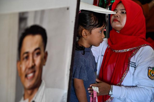 A health worker measures the growth of a child during a monthly medical check-up program for children at an integrated services centre in Banda Aceh on August 10, 2026. (Photo by CHAIDEER MAHYUDDIN / AFP)