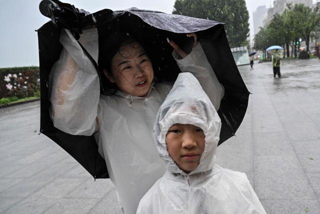 People visit the Bund amid heavy rain a day after Typhoon Dolphin made landfall in Shanghai on August 10, 2026. (Photo by Hector RETAMAL / AFP)