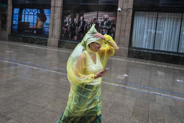 A woman visits the Bund amid heavy rain a day after Typhoon Dolphin made landfall in Shanghai on August 10, 2026. (Photo by Hector RETAMAL / AFP)