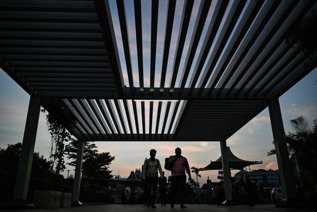 People walk along a footpath early morning in Chennai on August 10, 2026. (Photo by R. Satish BABU / AFP)