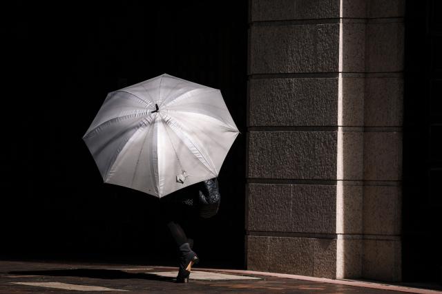 A woman holds an umbrella as she walks on a footpath on a winter's day in central Sydney on August 10, 2026. (Photo by DAVID GRAY / AFP)
