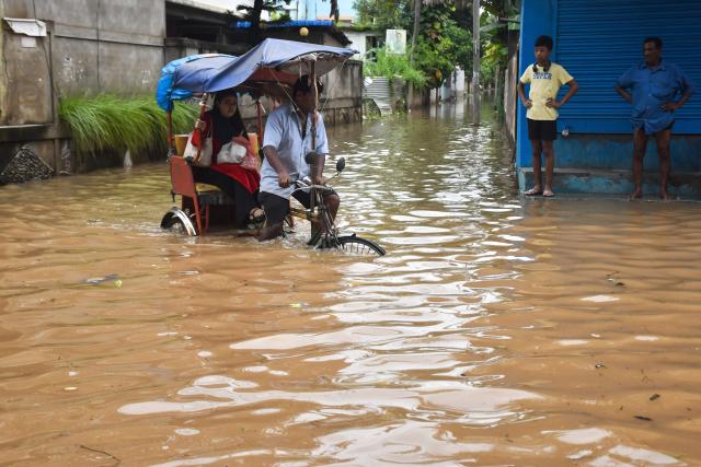 A resident commutes in a cycle rickshaw through a flooded street following heavy rainfall in Guwahati on August 9, 2026. Floods in India's northeast have killed nearly 100 people, according to an official toll update on August 7, with villages buried in mud after one of Assam state's worst deluges in years. (Photo by Biju BORO / AFP)