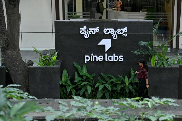 A pedestrian walks past a signage of the Indian financial technology company Pine Labs, displayed outside their office in Bengaluru on August 10, 2026. (Photo by Idrees MOHAMMED / AFP)