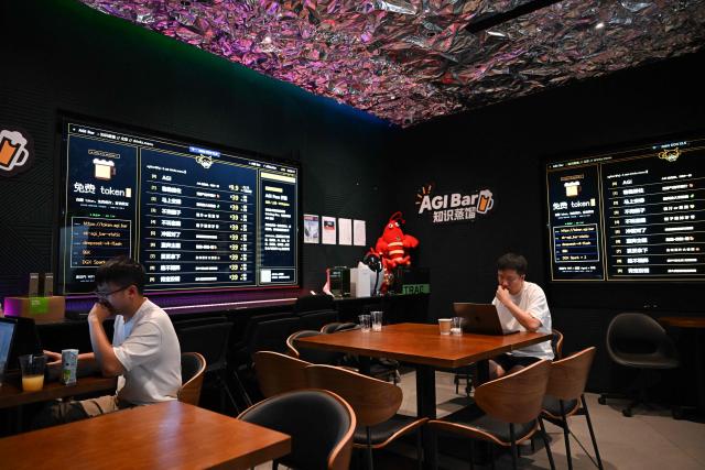 Customers work at AGI Bar in Beijing's in Zhongguancun district on August 9, 2026. Artificial intelligence users are shopping around as US giants face fierce competition from Chinese rivals -- and in Beijing's tech district, drinkers at an AI-themed bar can even plug in to DeepSeek for free. (Photo by Pedro PARDO / AFP) / To go with AFP story  China-US-technology-AI-business, FOCUS by Luna Lin and Thomas Urbain