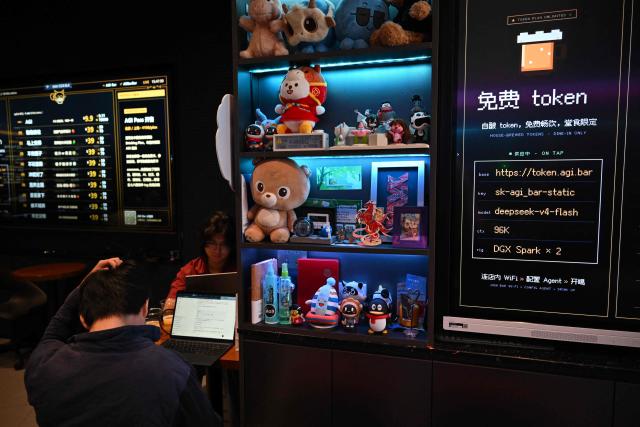 A customer works at AGI Bar in Beijing's in Zhongguancun district on August 9, 2026. Artificial intelligence users are shopping around as US giants face fierce competition from Chinese rivals -- and in Beijing's tech district, drinkers at an AI-themed bar can even plug in to DeepSeek for free. (Photo by Pedro PARDO / AFP) / To go with AFP story  China-US-technology-AI-business, FOCUS by Luna Lin and Thomas Urbain