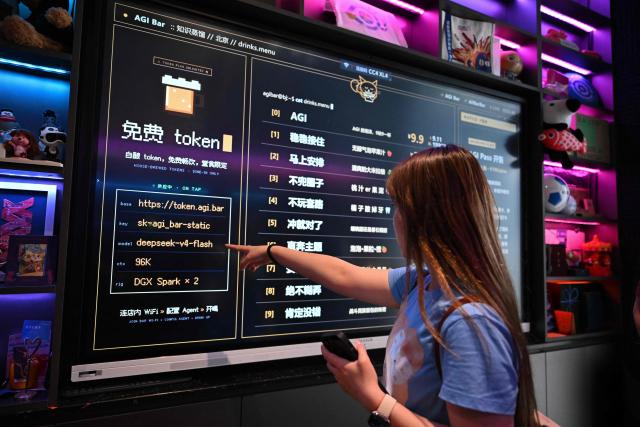A customer looks at a board with the menu at AGI Bar in Beijing's in Zhongguancun district on August 9, 2026. Artificial intelligence users are shopping around as US giants face fierce competition from Chinese rivals -- and in Beijing's tech district, drinkers at an AI-themed bar can even plug in to DeepSeek for free. (Photo by Pedro PARDO / AFP) / To go with AFP story  China-US-technology-AI-business, FOCUS by Luna Lin and Thomas Urbain