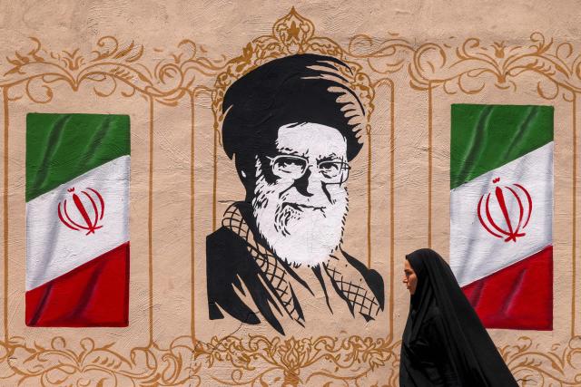 A woman walks past a mural depicting Iran's late supreme leader Ali Khamenei at Valiasr Square in central Tehran on August 8, 2026. Hopes for an imminent US-Iran deal to end the blockage of the Strait of Hormuz added to optimism that oil and gas, along with other key products, would again start flowing freely after more than five months of war. (Photo by ATTA KENARE / AFP) / 