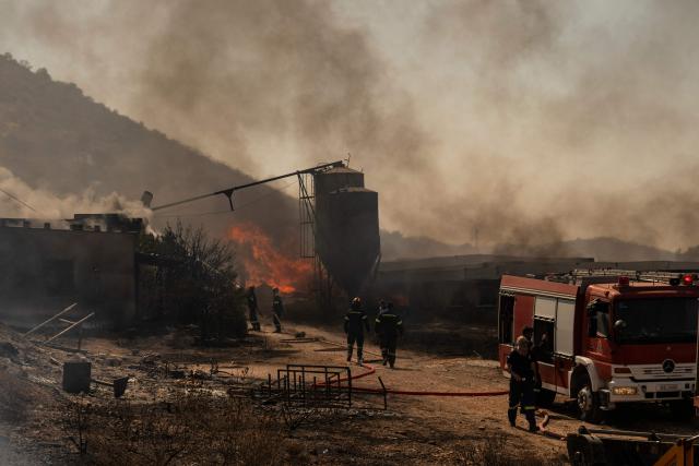 Firemen work to extinguish a fire that broke out at a livestock facility near Kouvaras, south of Athens, on August 10, 2026. (Photo by Aris MESSINIS / AFP)
