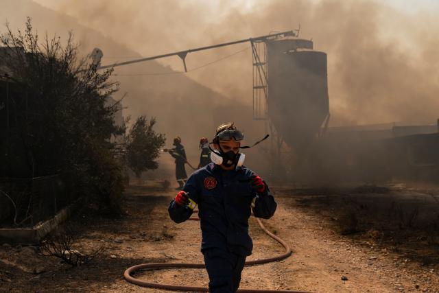 Firemen work to extinguish a fire that broke out at a livestock facility near Kouvaras, south of Athens, on August 10, 2026. (Photo by Aris MESSINIS / AFP)
