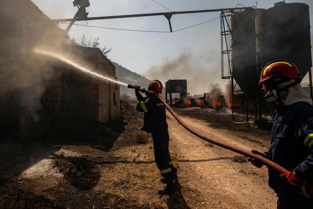 Firemen work to extinguish a fire that broke out at a livestock facility near Kouvaras, south of Athens, on August 10, 2026. (Photo by Aris MESSINIS / AFP)