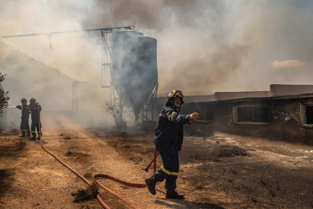 Firemen work to extinguish a fire that broke out at a livestock facility near Kouvaras, south of Athens, on August 10, 2026. (Photo by Aris MESSINIS / AFP)