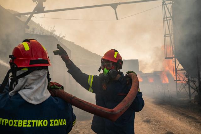 Firemen work to extinguish a fire that broke out at a livestock facility near Kouvaras, south of Athens, on August 10, 2026. (Photo by Aris MESSINIS / AFP)