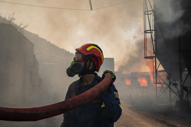 Firemen work to extinguish a fire that broke out at a livestock facility near Kouvaras, south of Athens, on August 10, 2026. (Photo by Aris MESSINIS / AFP)