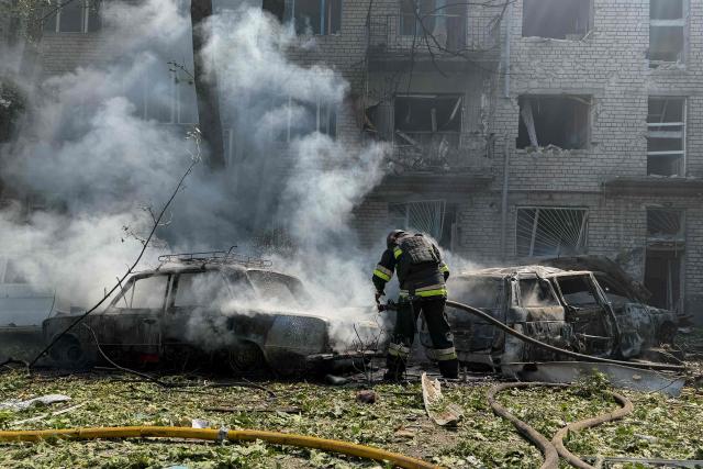 A Ukrainian firefighter puts off the fire in a car next to a damaged residential building at the site of a Russian airstrike in Zaporizhzhia on August 10, 2026, amid the Russian invasion of Ukraine. (Photo by Darya NAZAROVA / AFP)