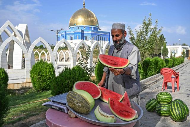 An Afghan vendor cuts watermelons as he waits for customers at the Wazir Akbar Khan hilltop in Kabul on August 10, 2026. (Photo by Wakil KOHSAR / AFP)