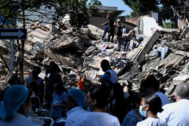 People work on a collapsed building after an earthquake in Cali, Colombia on August 10, 2026. A powerful earthquake rocked Colombia and neighboring Latin American countries on August 10, 2026, with medical teams rushing to help victims after buildings were damaged or collapsed in several cities. The Colombian geological service and its American counterpart USGS put the magnitude at 7.4, with an epicenter 100 km (60 miles) underground in the west of the country. Colombia had initially put it at 6.6. (Photo by Joaquin SARMIENTO / AFP)