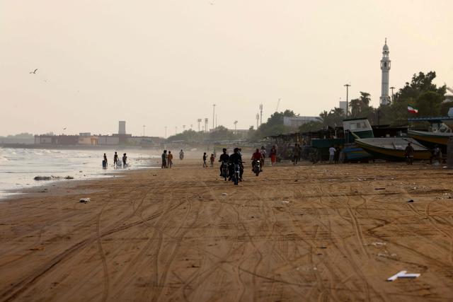 Iranians ride their motorbikes along the seashore in the port city of Bandar Abbas, in southern Iran on August 10, 2026. The US President signalled on August 9 that he was prepared to let economic pressure mount against Iran, apparently backing away from more military strikes after Tehran issued a list of demands for opening the Strait of Hormuz. His remarks came after Iran issued over the weekend a list of conditions to reopen the Strait of Hormuz, which has remained largely closed since the start of the Middle East war in late February. (Photo by Atta KENARE / AFP) / 