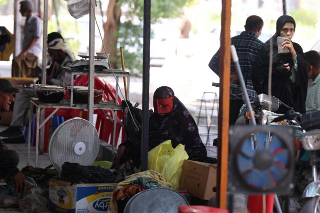 An Iranian woman wears a rigid mask known as a boregheh or battoulah in a market in Minab, in southern Iran on August 10, 2026. The US President signalled on August 9 that he was prepared to let economic pressure mount against Iran, apparently backing away from more military strikes after Tehran issued a list of demands for opening the Strait of Hormuz. His remarks came after Iran issued over the weekend a list of conditions to reopen the Strait of Hormuz, which has remained largely closed since the start of the Middle East war in late February. (Photo by Atta KENARE / AFP) / 