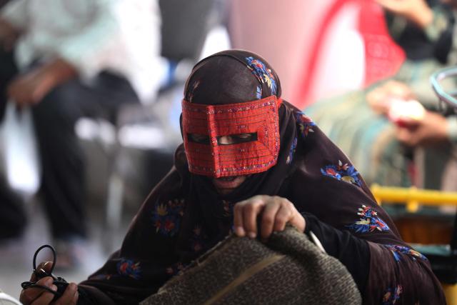 An Iranian woman wears a rigid mask known as a boregheh or battoulah in a market in Minab, in southern Iran on August 10, 2026. The US President signalled on August 9 that he was prepared to let economic pressure mount against Iran, apparently backing away from more military strikes after Tehran issued a list of demands for opening the Strait of Hormuz. His remarks came after Iran issued over the weekend a list of conditions to reopen the Strait of Hormuz, which has remained largely closed since the start of the Middle East war in late February. (Photo by Atta KENARE / AFP) / 