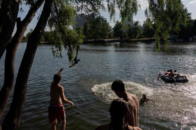 Teenagers play on a rope swing as they swim in Telbin lake on a hot day in Kyiv on August 10, 2026, amid the Russian invasion of Ukraine. (Photo by Tetiana DZHAFAROVA / AFP)