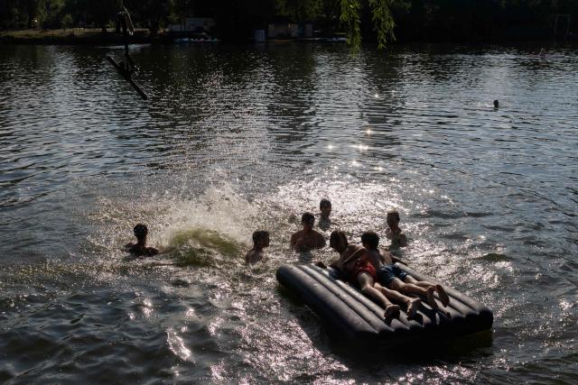 Teenagers swim in Telbin lake on a hot day in Kyiv on August 10, 2026, amid the Russian invasion of Ukraine. (Photo by Tetiana DZHAFAROVA / AFP)