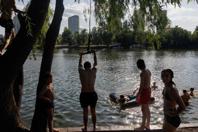 Teenagers play on a rope swing as they swim in Telbin lake on a hot day in Kyiv on August 10, 2026, amid the Russian invasion of Ukraine. (Photo by Tetiana DZHAFAROVA / AFP)