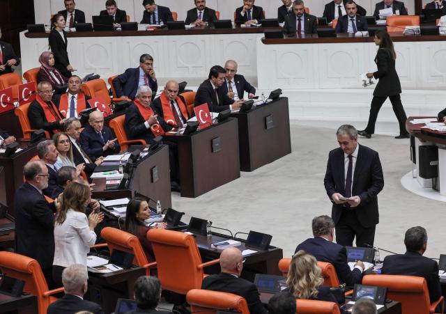 Turkish Nationalist Movement Party's (MHP) leader Devlet Bahceli (5th L) and Equality and Democracy (DEM) Party co-leader Tuncer Bakirhan (R, standing) take part in a voting session on a bill offering limited amnesty for Kurdish PKK militants at Grand National Assembly of Turkey in Ankara on August 10, 2026. Turkish lawmakers on August 10, 2026, voted through a bill offering limited amnesty for Kurdish PKK militants in a first legislative step to end decades of deadly violence, footage from parliament showed. The bill offering limited amnesty to Kurdish fighters remained silent on the fate of jailed PKK leader Abdullah Ocalan, who championed the process. (Photo by Adem ALTAN / AFP)