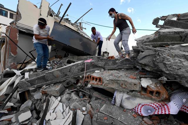 People pull furniture out of the rubble of a collapsed building after an earthquake in Pereira, Colombia on August 10, 2026. A magnitude 7.4 earthquake struck Colombia on August 10, 2026, and killed at least 111 people, damaged more than 1,500 buildings, and left an unknown number of people buried under rubble. The government declared a state of emergency to attend to the quake that shook several cities across the coffee-producing region, the Pacific coast, and neighboring Latin American countries, sending terrified residents racing into the street. (Photo by Jaime SALDARRIAGA / AFP)