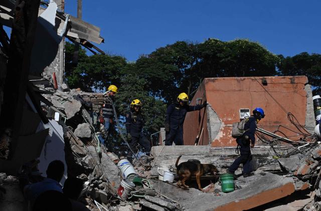 Rescuers look for survivors amid the rubble of a collapsed building after an earthquake in Cali, Colombia on August 10, 2026. A magnitude 7.4 earthquake struck Colombia on August 10, 2026, and killed at least 111 people, damaged more than 1,500 buildings, and left an unknown number of people buried under rubble. The government declared a state of emergency to attend to the quake that shook several cities across the coffee-producing region, the Pacific coast, and neighboring Latin American countries, sending terrified residents racing into the street. (Photo by Joaquin SARMIENTO / AFP)