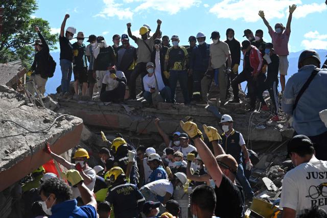 People and rescuers look for survivors amid the rubble of a collapsed building after an earthquake in Cali, Colombia on August 10, 2026. A magnitude 7.4 earthquake struck Colombia on August 10, 2026, and killed at least 111 people, damaged more than 1,500 buildings, and left an unknown number of people buried under rubble. The government declared a state of emergency to attend to the quake that shook several cities across the coffee-producing region, the Pacific coast, and neighboring Latin American countries, sending terrified residents racing into the street. (Photo by Joaquin SARMIENTO / AFP)
