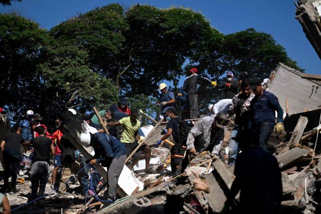 People and rescuers look for survivors amid the rubble of a collapsed building after an earthquake in Cali, Colombia on August 10, 2026. A magnitude 7.4 earthquake struck Colombia on August 10, 2026, and killed at least 111 people, damaged more than 1,500 buildings, and left an unknown number of people buried under rubble. The government declared a state of emergency to attend to the quake that shook several cities across the coffee-producing region, the Pacific coast, and neighboring Latin American countries, sending terrified residents racing into the street. (Photo by Joaquin SARMIENTO / AFP)