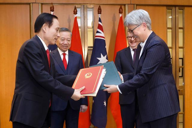 Australian Foreign Minister Penny Wong (R) exchanges documents with Vietnamese Foreign Minister Le Hoai Trung (L) as Australian Prime Minister Anthony Albanese and Vietnamese General Secretary and President To Lam (2nd L) look on during a document exchange ceremony at Parliament House in Canberra on August 11, 2026.. (Photo by hilary wardhaugh / AFP)