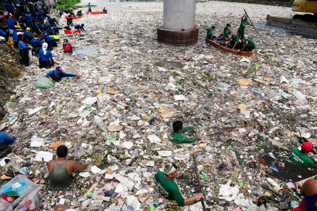 Workers collect rubbish washed up on a river at the height of heavy rains enhanced by the Southwest monsoon days before, near a shopping complex in Paranaque City, suburban Manila on August 11, 2026. Floods, landslides and accidents driven by a nine-day downpour equivalent to more than a month's worth of rain in some areas have killed at least 16 people in the northern Philippines, rescuers said on August 10. (Photo by Ted ALJIBE / AFP)