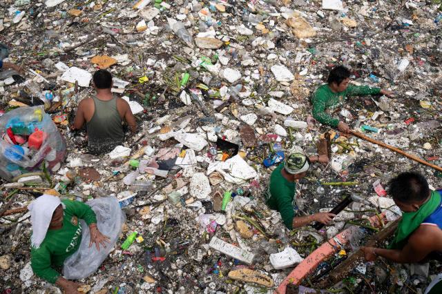 TOPSHOT - Workers collect rubbish washed up on a river at the height of heavy rains enhanced by the Southwest monsoon days before, near a shopping complex in Paranaque City, suburban Manila on August 11, 2026. Floods, landslides and accidents driven by a nine-day downpour equivalent to more than a month's worth of rain in some areas have killed at least 16 people in the northern Philippines, rescuers said on August 10. (Photo by Ted ALJIBE / AFP)