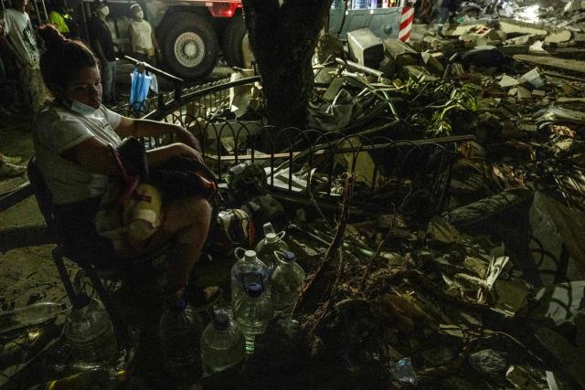 A women waits for information about a missing relative as rescuers search for survivors at a collapsed building after an earthquake in Pereira, Colombia on August 10, 2026. A magnitude 7.4 earthquake struck Colombia on August 10, 2026, and killed at least 111 people, damaged more than 1,500 buildings, and left an unknown number of people buried under rubble. The government declared a state of emergency to attend to the quake that shook several cities across the coffee-producing region, the Pacific coast, and neighboring Latin American countries, sending terrified residents racing into the street. (Photo by Luis ACOSTA / AFP)