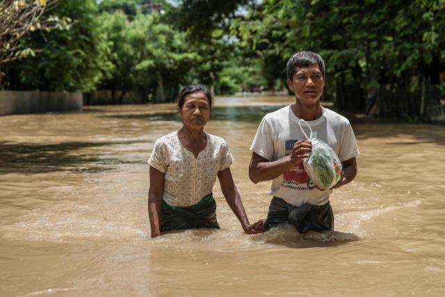 People wade through a flooded area due to monsoon rains and rising river water levels in Wetlet, Myanmar’s Sagaing region on August 10, 2026. (Photo by AFP)