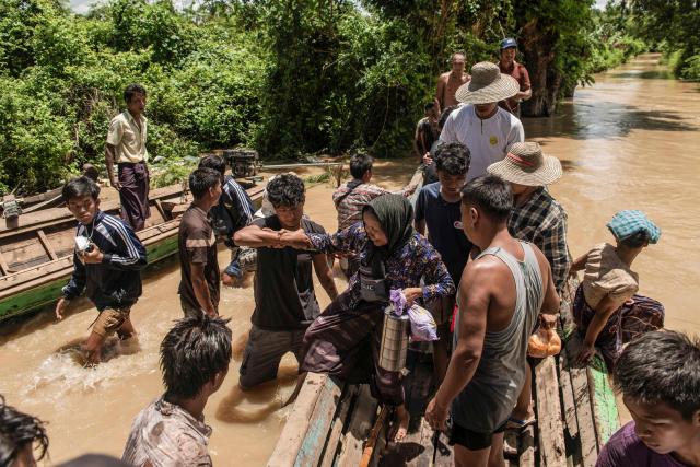 TOPSHOT - People cross a flooded area on a boat due to monsoon rains and rising river water levels in Wetlet, Myanmar’s Sagaing region on August 10, 2026. (Photo by AFP)