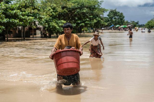 A man carries a child in a bucket while walking through a flooded area due to monsoon rains and rising river water levels in Wetlet, Myanmar’s Sagaing region on August 10, 2026. (Photo by AFP)