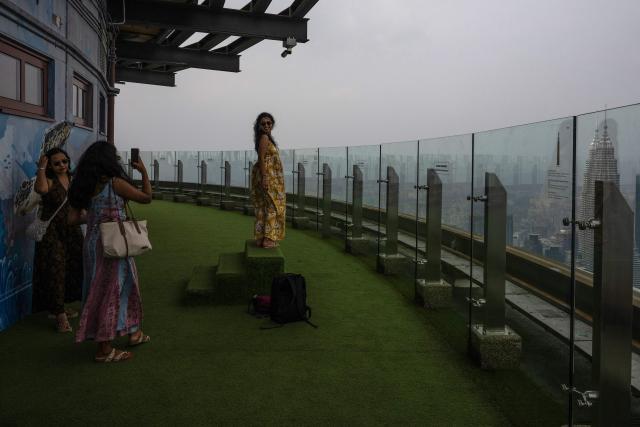 Visitors take pictures from the KL Tower as the city skyline is covered in haze in Kuala Lumpur on August 11, 2026, as authorities in Malaysia warned of high levels of air pollution from regional wildfires. The Malaysian Meteorological Department urged people on August 11 affected by air pollution to stay indoors, with director-general Mohd Hisham Mohd Anip blaming a "cross-border haze phenomenon from Kalimantan," the Indonesian portion of the island of Borneo. (Photo by Mohd Rasfan / AFP)