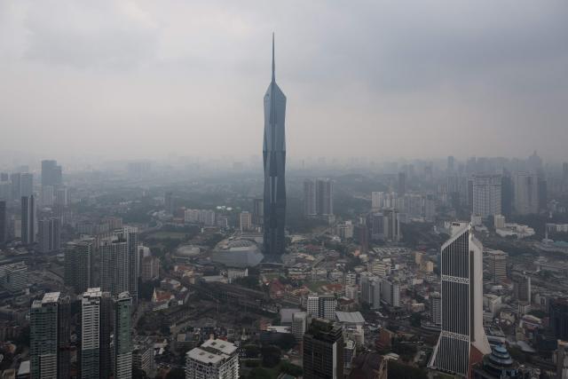 Warisan Merdeka Tower (KL118) (C) and commercial buildings are covered in haze in Kuala Lumpur on August 11, 2026, as authorities in Malaysia warned of high levels of air pollution from regional wildfires. The Malaysian Meteorological Department urged people on August 11 affected by air pollution to stay indoors, with director-general Mohd Hisham Mohd Anip blaming a "cross-border haze phenomenon from Kalimantan," the Indonesian portion of the island of Borneo. (Photo by Mohd Rasfan / AFP)