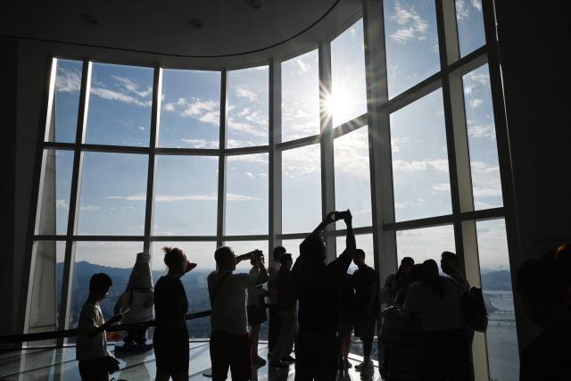 People look at views across the city from an observation deck at the Lotte World Tower in Seoul on August 11, 2026. (Photo by GREG BAKER / AFP)