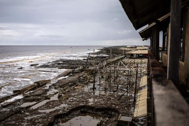 A general view of buildings destroyed by coastal erosion, seen from the King's Palace in Ayetoro, Ondo State, on August 6, 2026. The coastal community of Ayetoro, in Nigeria's southwestern Ondo State, has become one of the country's most visible examples of the vulnerability of communities living along the Atlantic Ocean to coastal erosion and rising waters. Since the early 2000s, coastal erosion in Ayetoro has progressively intensified, with the Atlantic Ocean gradually encroaching on the settlement, swallowing homes, schools, and other infrastructure, and forcing some residents to relocate several times. The ocean that the community has lived alongside for generations has become a constant threat, leaving families to rebuild further inland only to see the water reach them again. For many in Ayetoro, the question is no longer whether the sea will reach their home, but when. (Photo by OLYMPIA DE MAISMONT / AFP)