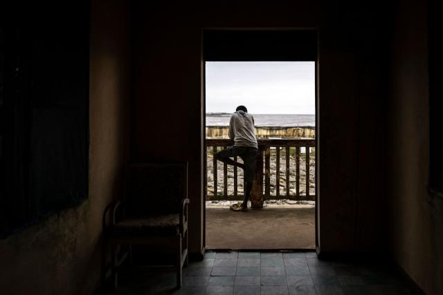A resident looks at buildings destroyed by coastal erosion from the King's Palace in Ayetoro, Ondo State, on August 6, 2026. The coastal community of Ayetoro, in Nigeria's southwestern Ondo State, has become one of the country's most visible examples of the vulnerability of communities living along the Atlantic Ocean to coastal erosion and rising waters. Since the early 2000s, coastal erosion in Ayetoro has progressively intensified, with the Atlantic Ocean gradually encroaching on the settlement, swallowing homes, schools, and other infrastructure, and forcing some residents to relocate several times. The ocean that the community has lived alongside for generations has become a constant threat, leaving families to rebuild further inland only to see the water reach them again. For many in Ayetoro, the question is no longer whether the sea will reach their home, but when. (Photo by OLYMPIA DE MAISMONT / AFP)